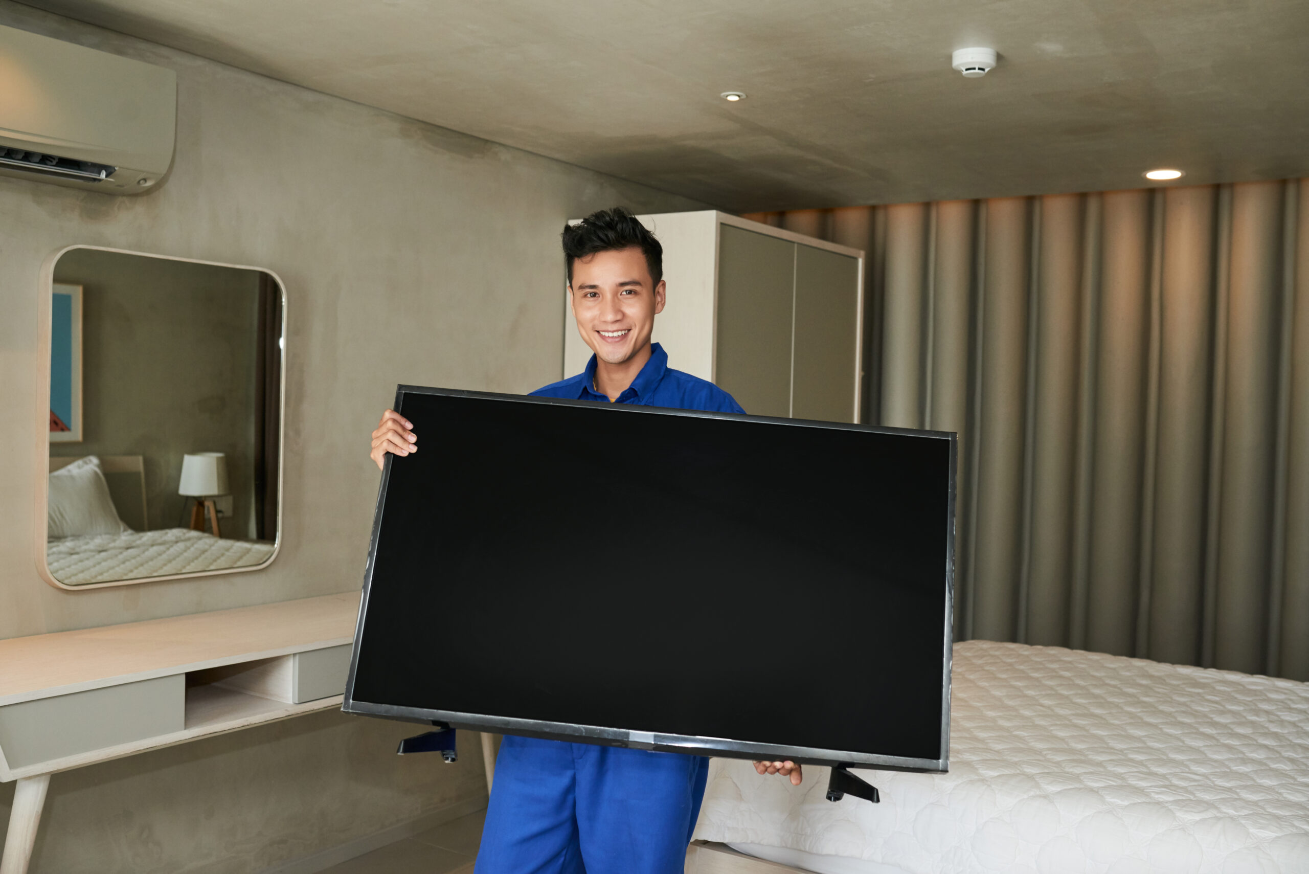 Portrait of happy Vietnamese technician withbig plasma television